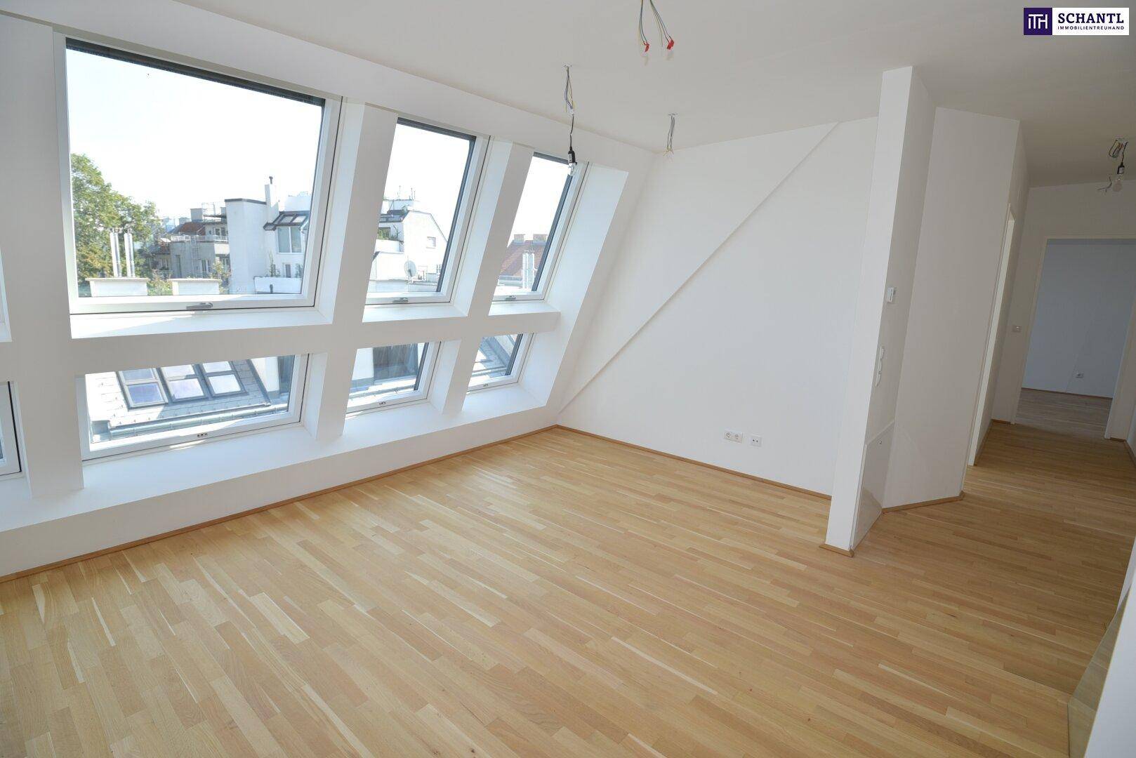 Lichtdurchfluteter Wohnbereich mit schrägen Wänden, großen Fenstern und neuem Holzparkettboden.