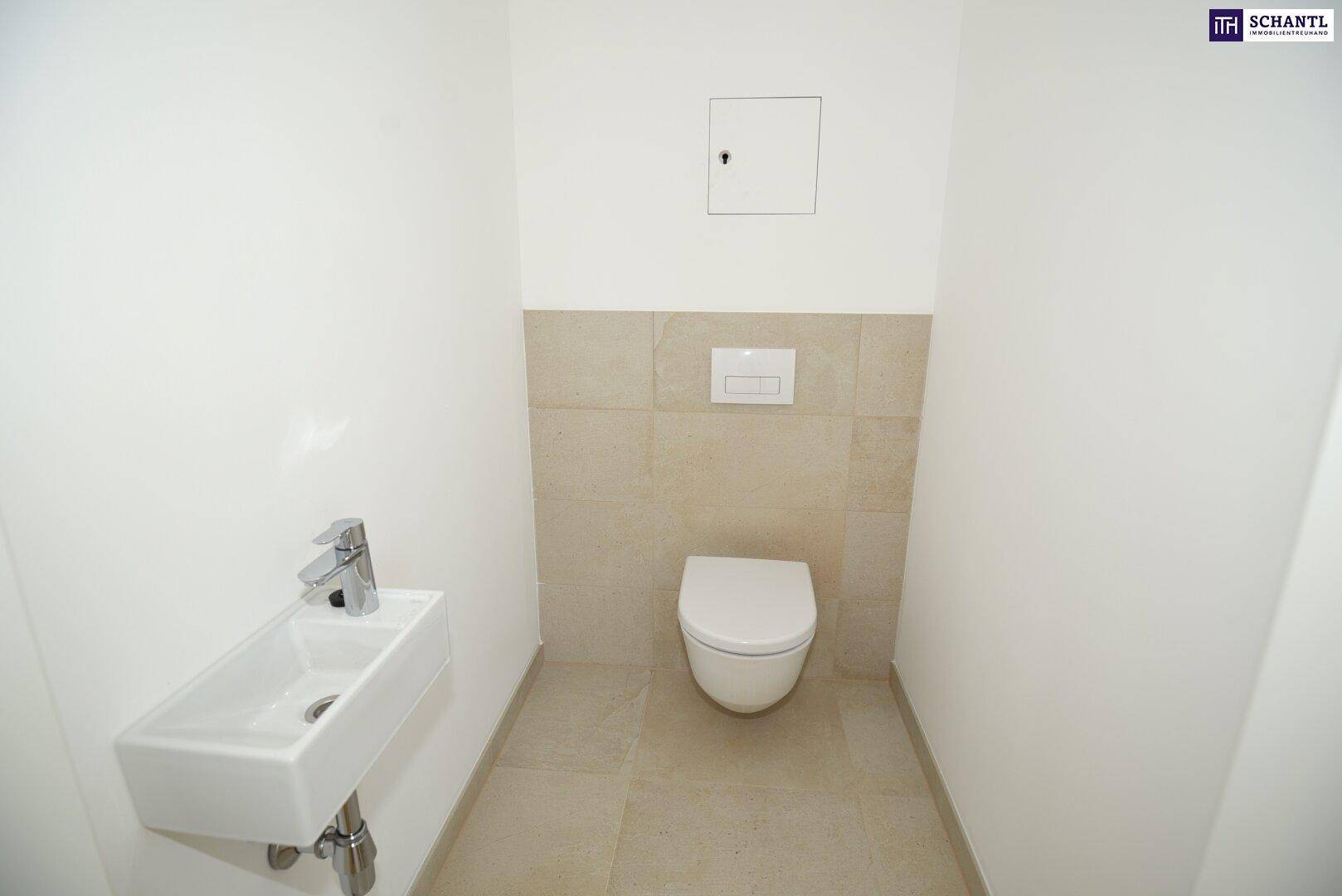 Separates Gäste-WC mit wandhängender Toilette und kleinem Waschbecken, in hellen Fliesen gehalten.