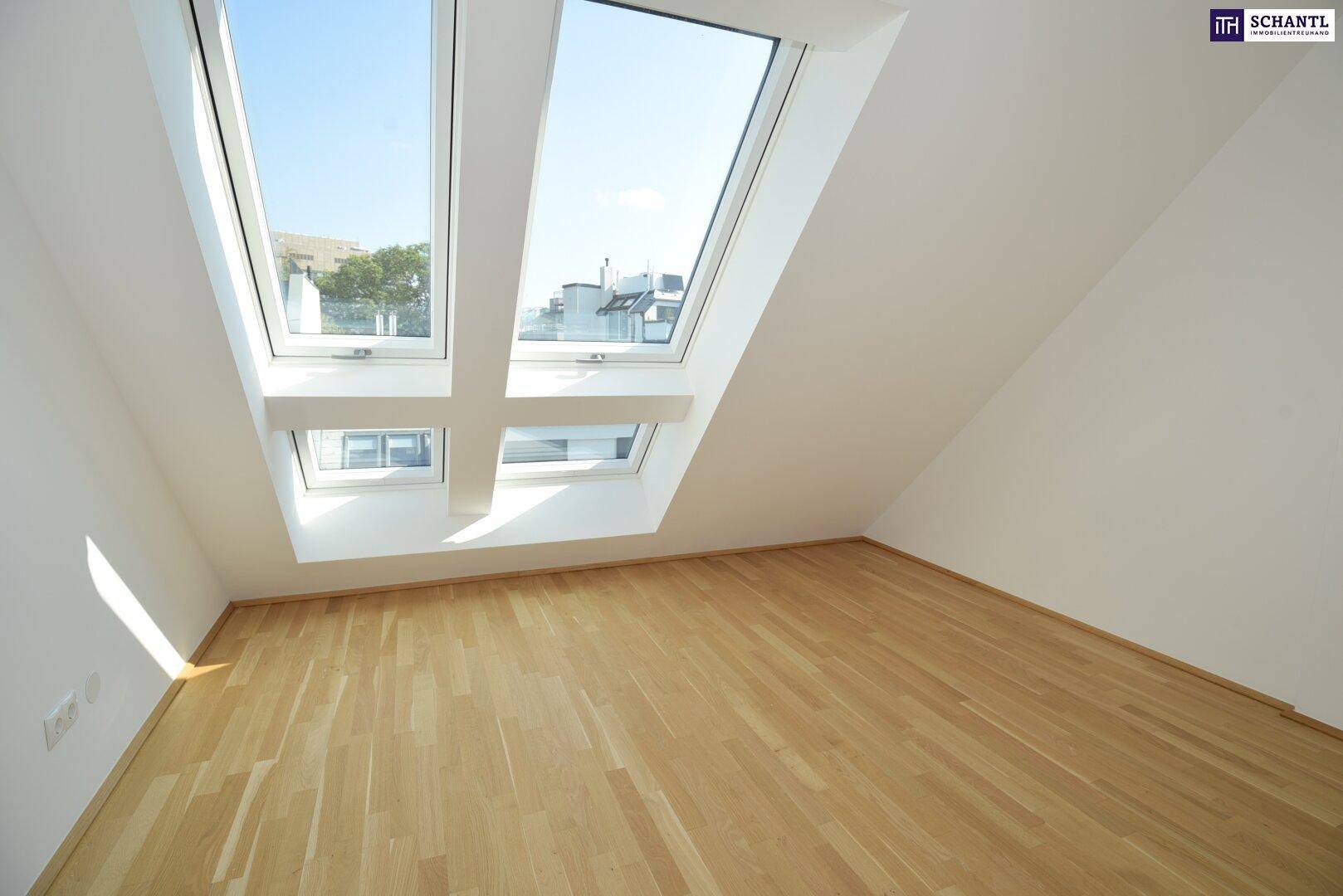 Helle Dachfenster lassen viel Tageslicht in den leeren Raum mit Holzparkettboden.