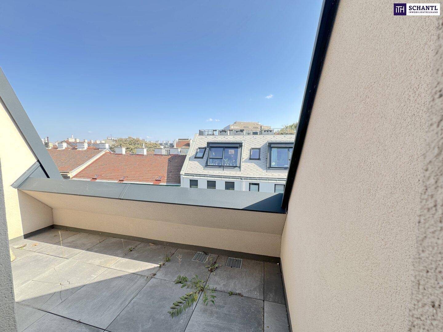 Sonniger Terrassenbereich mit Fliesenboden und Blick auf die umliegenden Dächer und Gebäude.