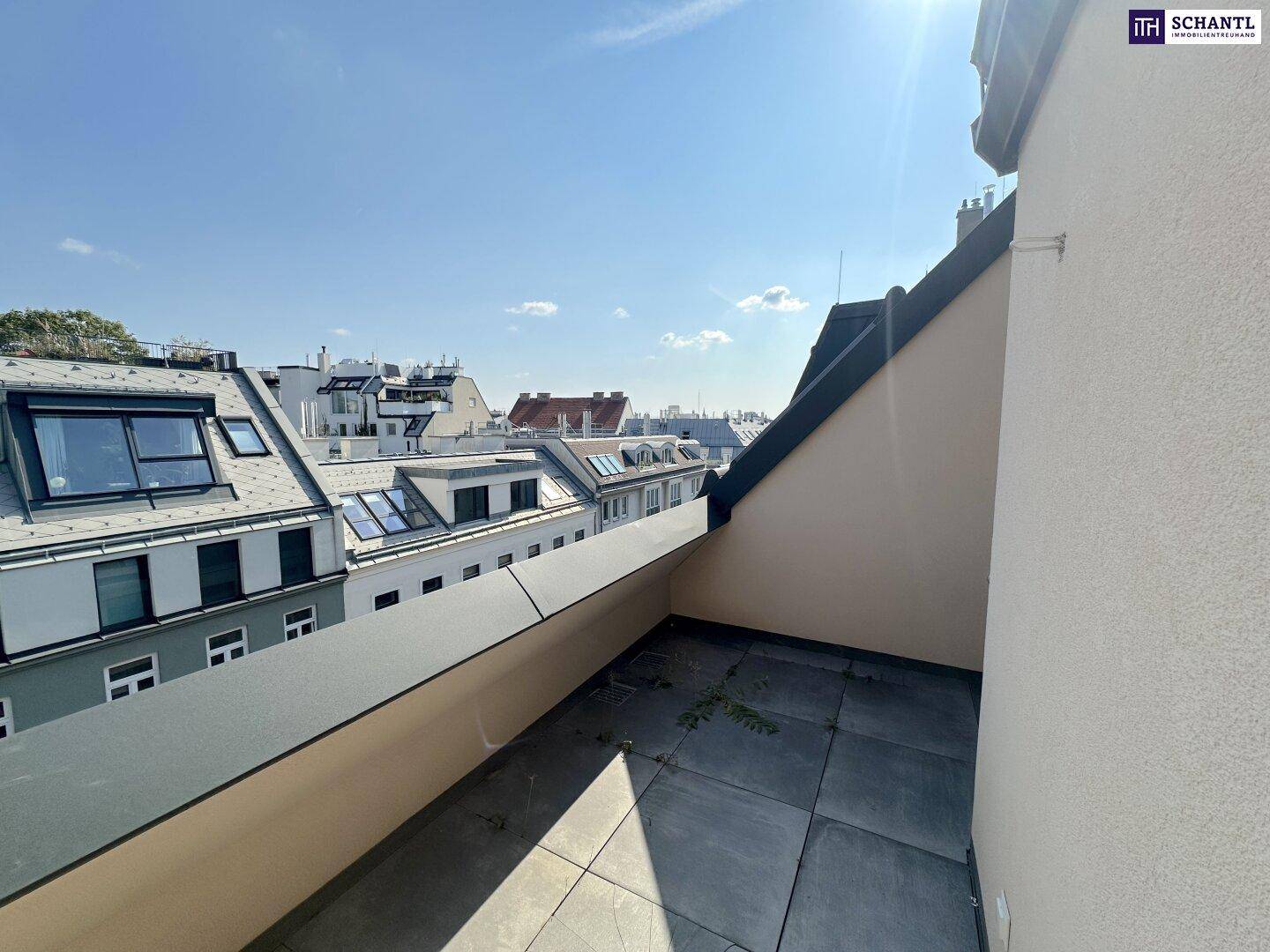 Geräumige Dachterrasse mit Fliesenboden und weitem Blick über die Dächer der Stadt unter strahlendem Sonnenschein.
