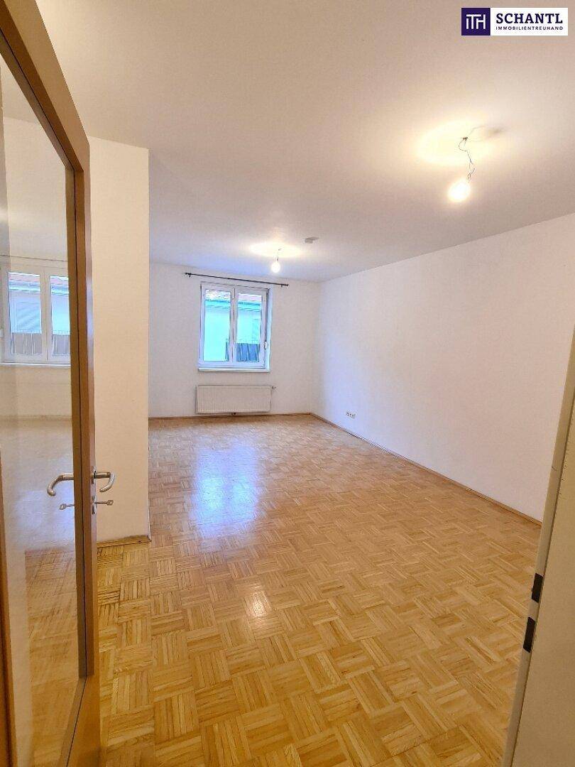 Heller Raum mit Parkettboden und Fenster, das Tageslicht in den Wohnbereich bringt.