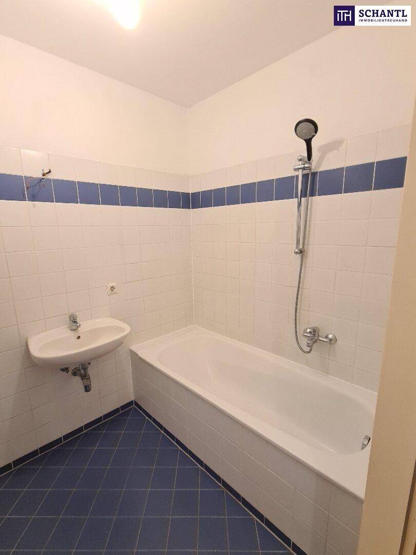 Gefliestes Badezimmer mit Badewanne und Duschvorrichtung, in einem gepflegten Zustand.