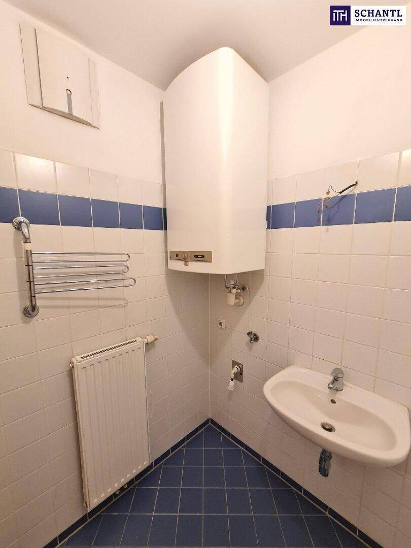 Badezimmer mit Waschbecken, Badewanne und Wandheizkörper, gefliest in Weiß und Blau.
