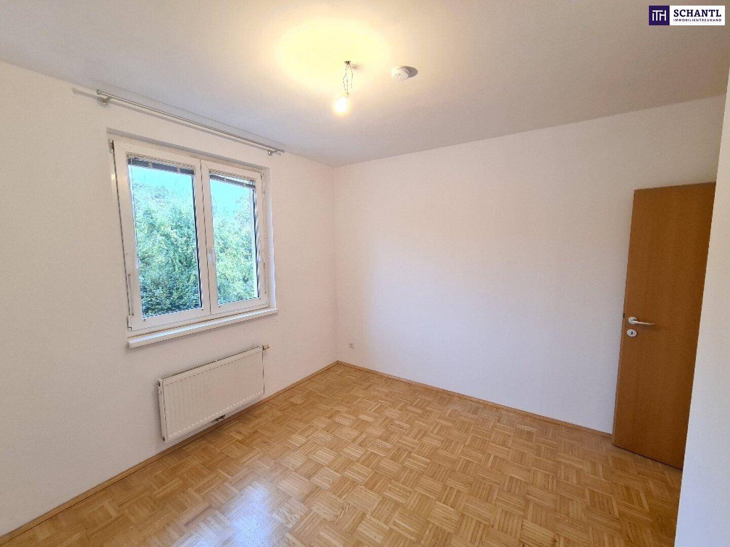 Ruhiges Schlafzimmer mit Parkettboden und Fenster, das einen Blick ins Grüne bietet.