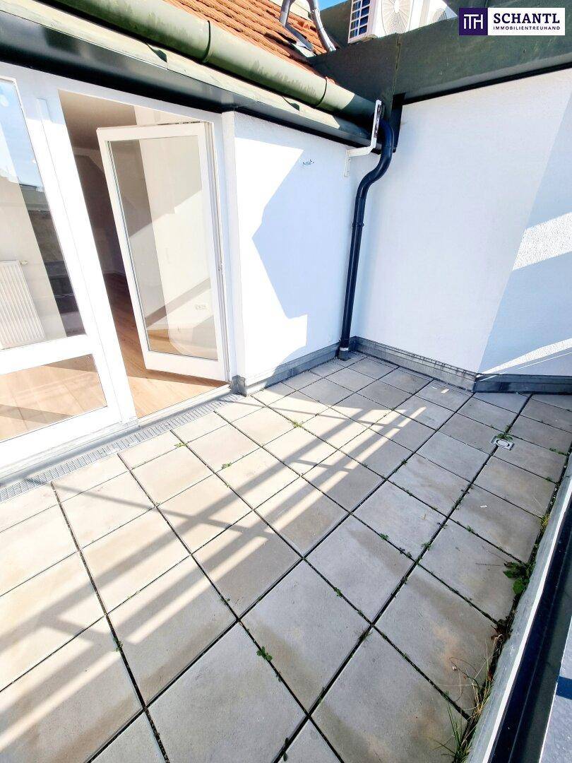 Kleiner Balkon mit Fliesenboden und Blick auf die umliegenden Gebäude unter blauem Himmel.