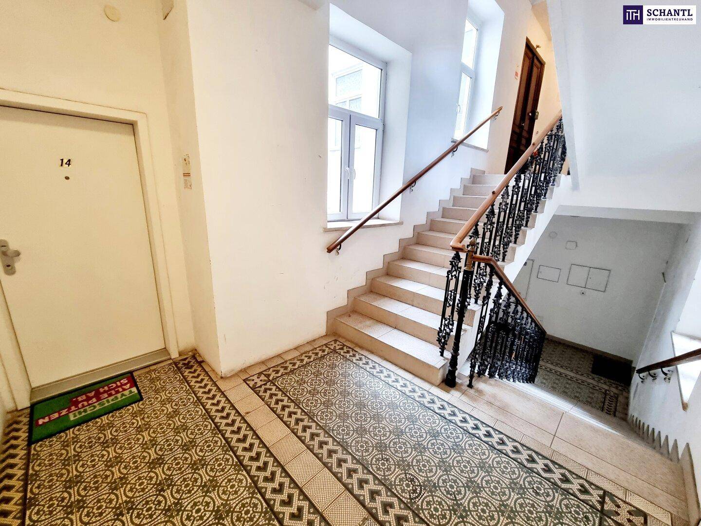 Historisches Treppenhaus mit kunstvollem Geländer und gemusterten Fliesenböden, gut erhalten.