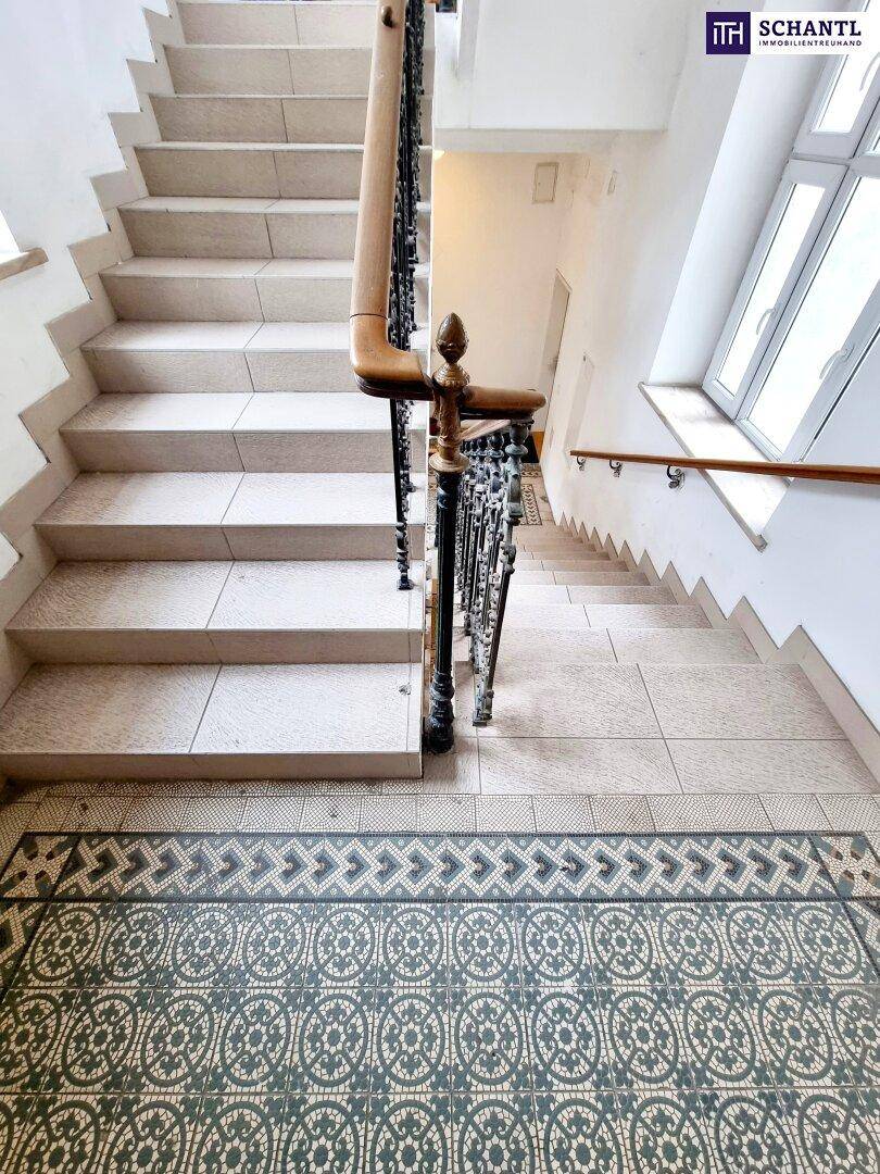 Detailansicht des historischen Treppenhauses mit gemusterten Fliesen und kunstvollem Geländer.