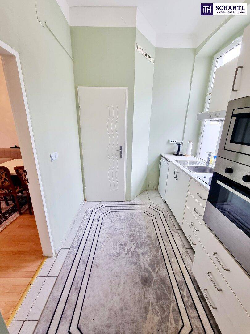Funktionale Küche mit weißen Schränken, Fliesenboden und einem Fenster mit Ausblick.