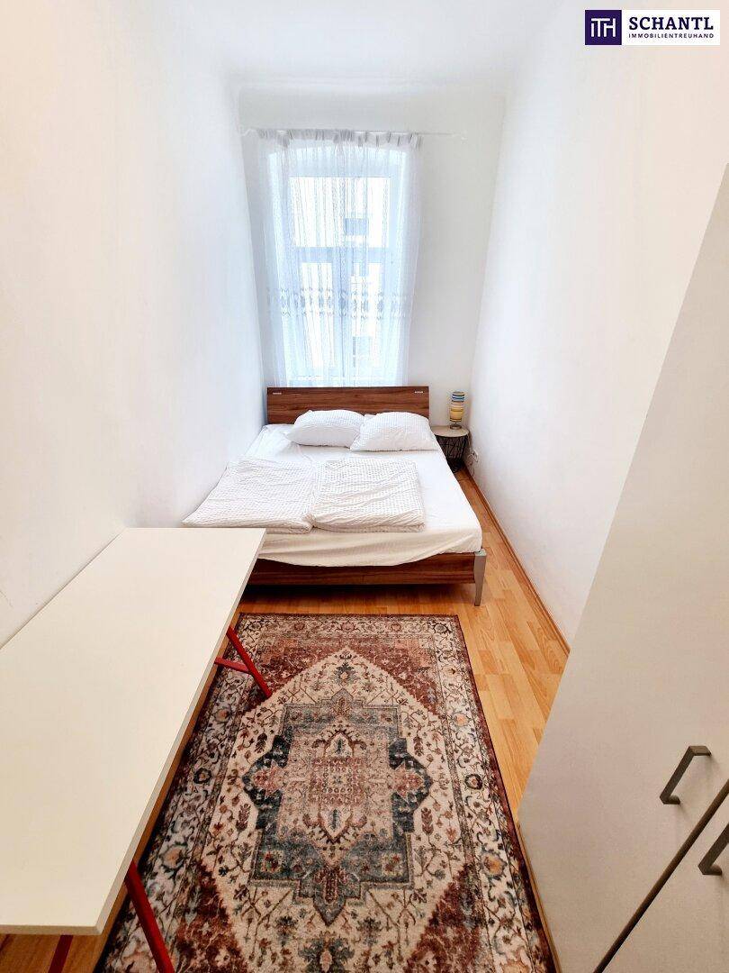 Schlichtes Schlafzimmer mit Holzbett, Parkettboden und einem Fenster für natürliches Licht.