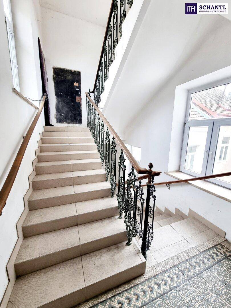 Elegantes Treppenhaus mit schmiedeeisernem Geländer und hellen Stufen, gut erhalten.