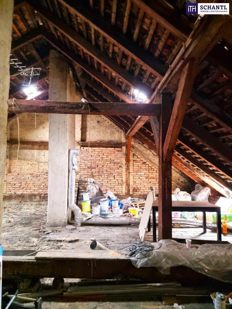Unausgebauter Dachbodenbereich mit sichtbaren Holzbalken und Ziegelwänden, ideal für zukünftige Projekte.