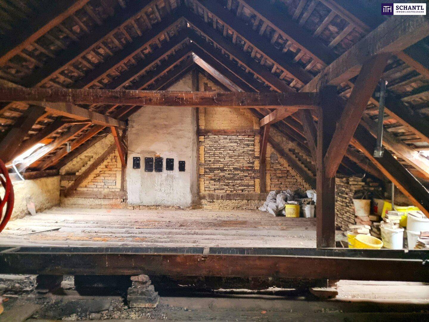 Großer Rohdachboden mit sichtbaren Holzbalken und Ziegelwänden, bereit für den Ausbau.