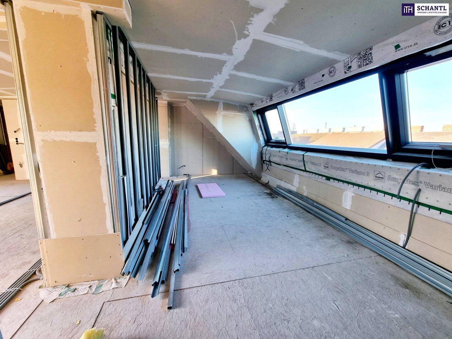 Dachgeschossraum im Rohbau mit schrägen Wänden und Dachfenstern, ideal für den Ausbau.