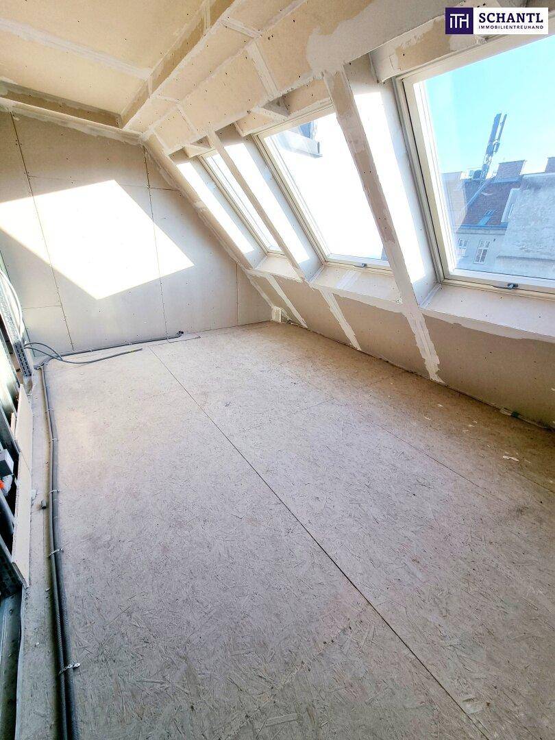 Heller Dachgeschossraum im Rohbau mit mehreren Dachfenstern und Blick auf die Umgebung.