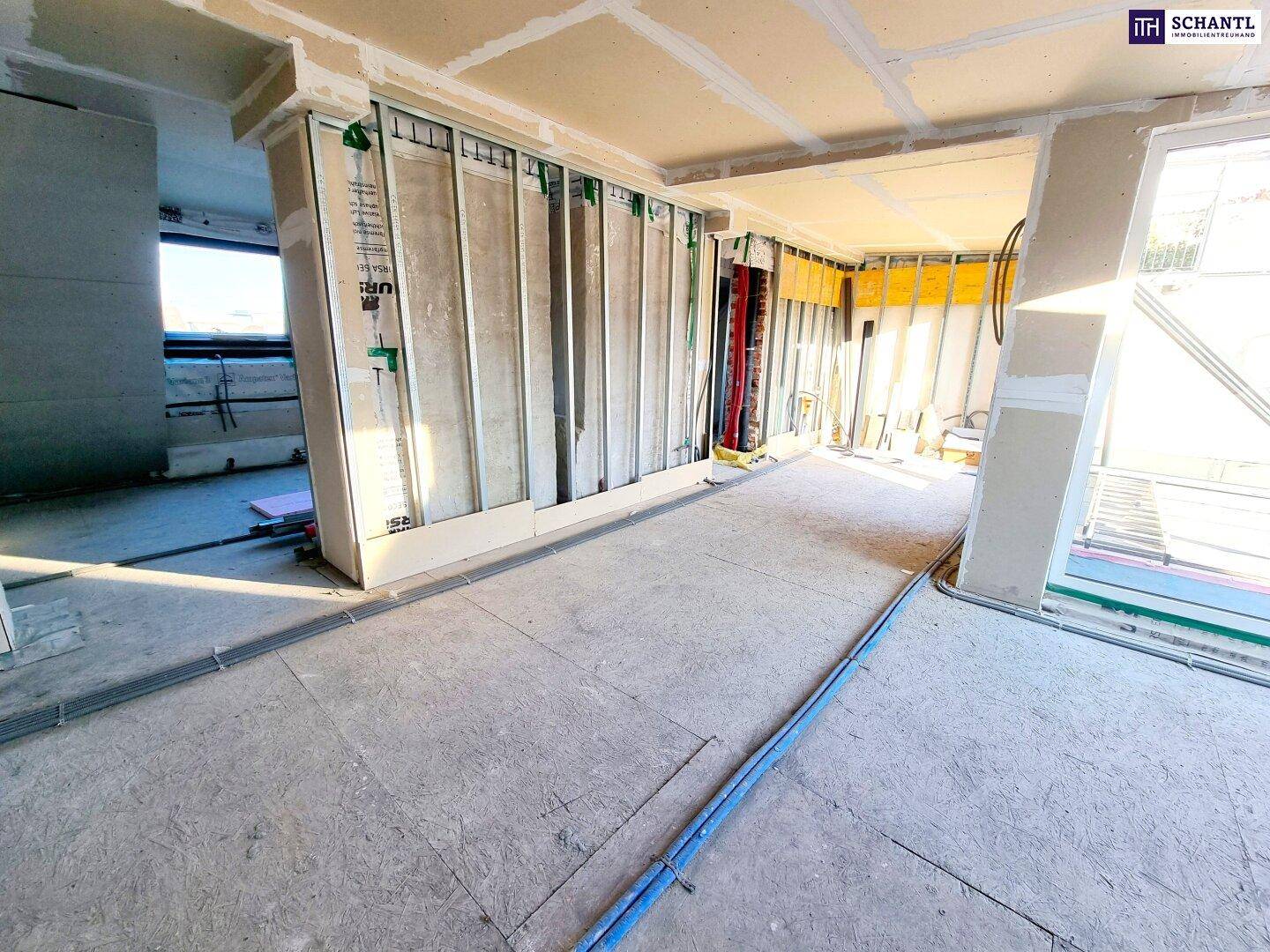 Innenraum im Rohbau mit Trockenbauwänden und Blick auf die Umgebung, bereit für den weiteren Ausbau.