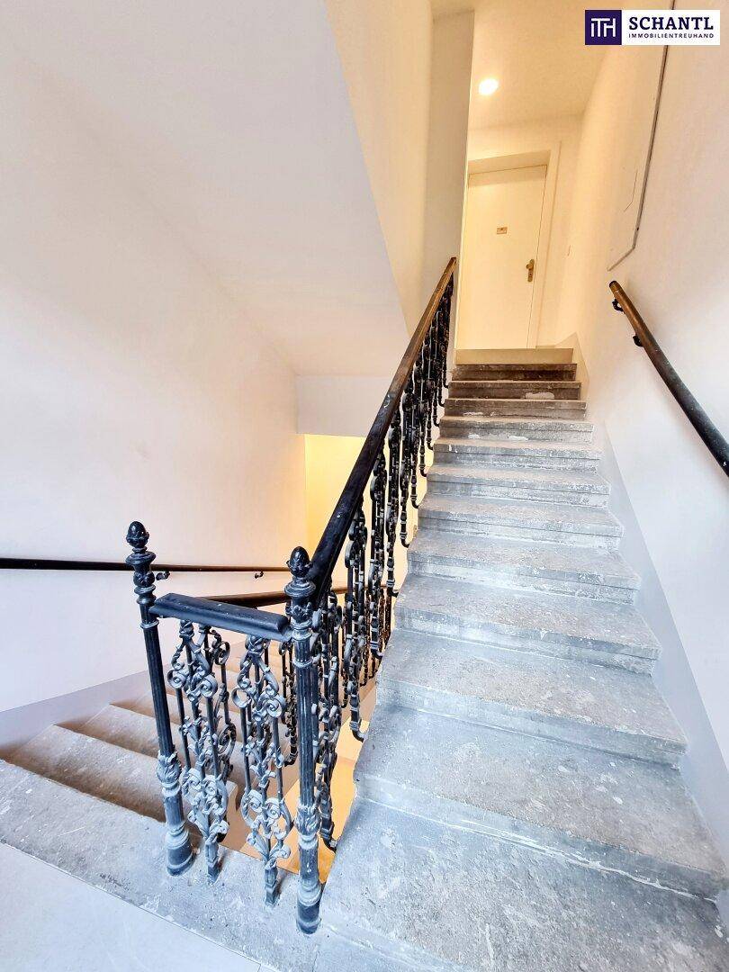 Elegantes Treppenhaus mit Steinstufen und einem verzierten schmiedeeisernen Handlauf.