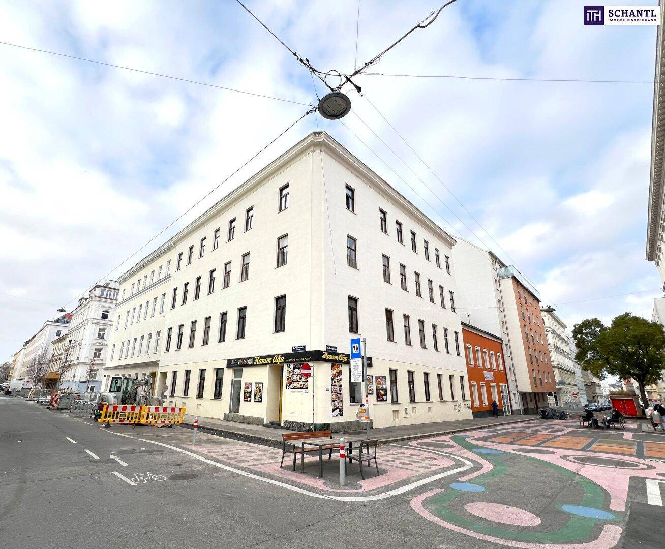 Weitwinkelansicht eines Eckgebäudes mit weißer Fassade und umliegender Stadtstraße.