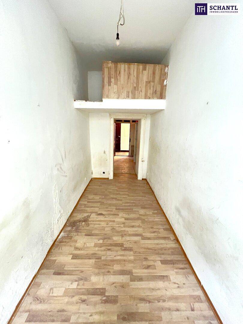 Langer, leerer Raum mit Holzboden und einer kleinen Holzkonstruktion im oberen Bereich, deutliche Gebrauchsspuren.