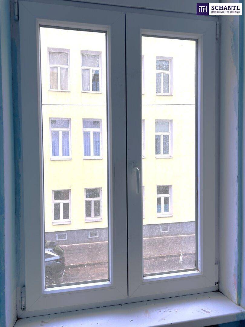 Fenster mit Blick auf die gegenüberliegende Gebäudefassade und die Straße.