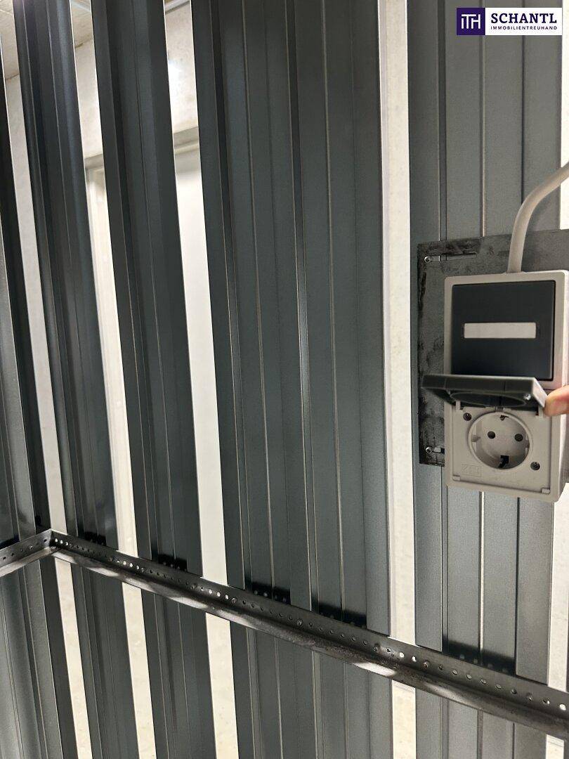 Elektrische Steckdose an einer Metallwand in einem einfachen Abstellraum oder Kellerabteil.