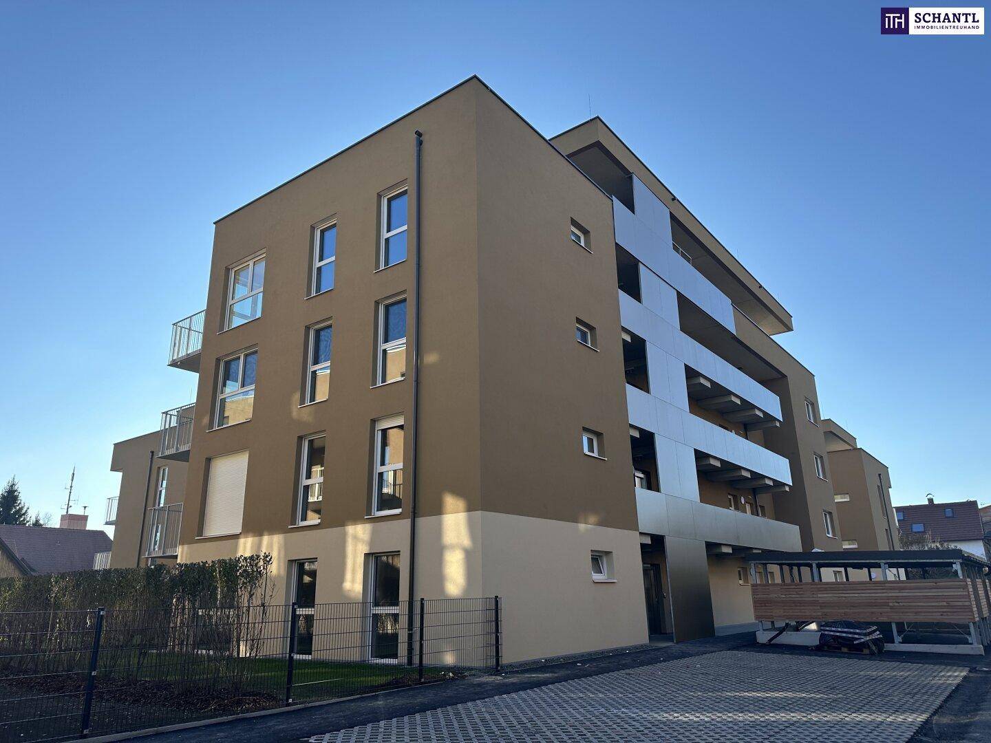 Modernes Apartmentgebäude mit markanter Fassadengestaltung und gepflastertem Parkbereich.
