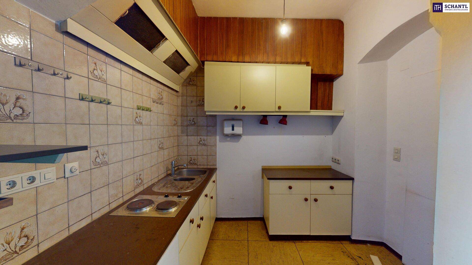 Küche mit Fliesenboden, Einbauschränken und Gasherd, mit Holzverkleidung an der Decke.