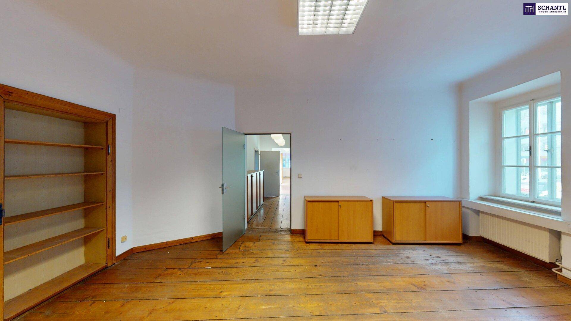 Leerer Büroraum mit Holzboden, Regalen und einem Fenster, bereit zur individuellen Einrichtung.