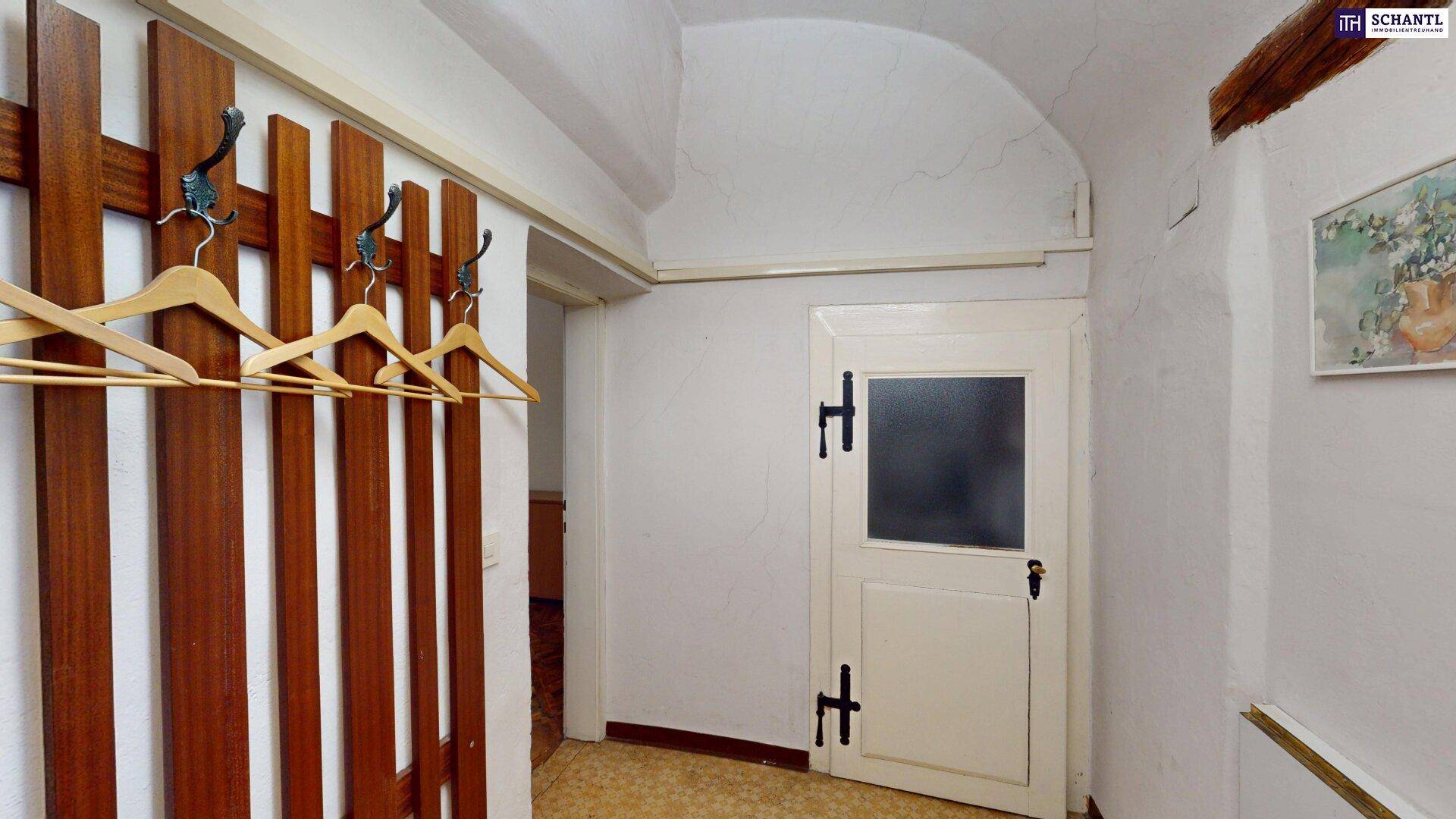 Eingangsbereich mit Garderobe, gewölbter Decke und einer Tür, die in einen weiteren Raum führt.