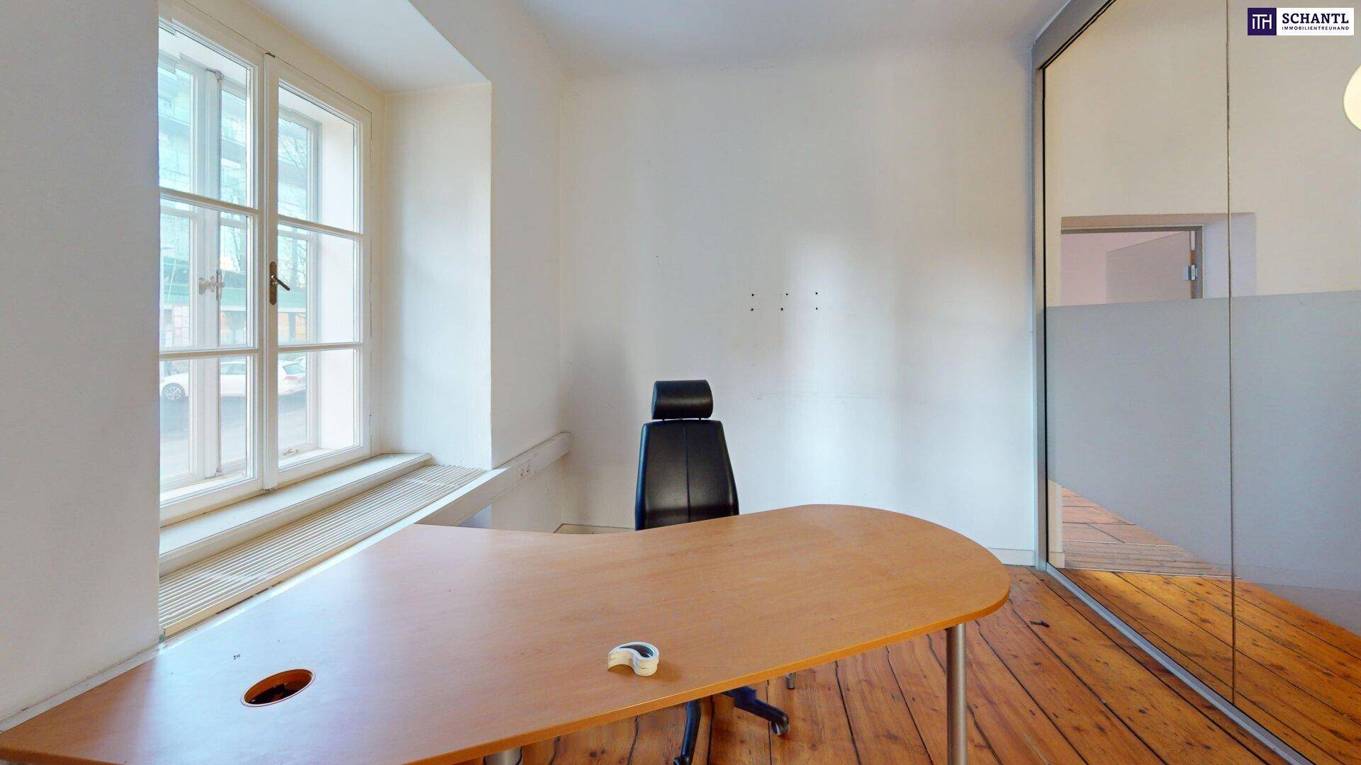 Büroraum mit Holzboden, Schreibtisch und einer Glaswand, die für Helligkeit und modernes Design sorgt.