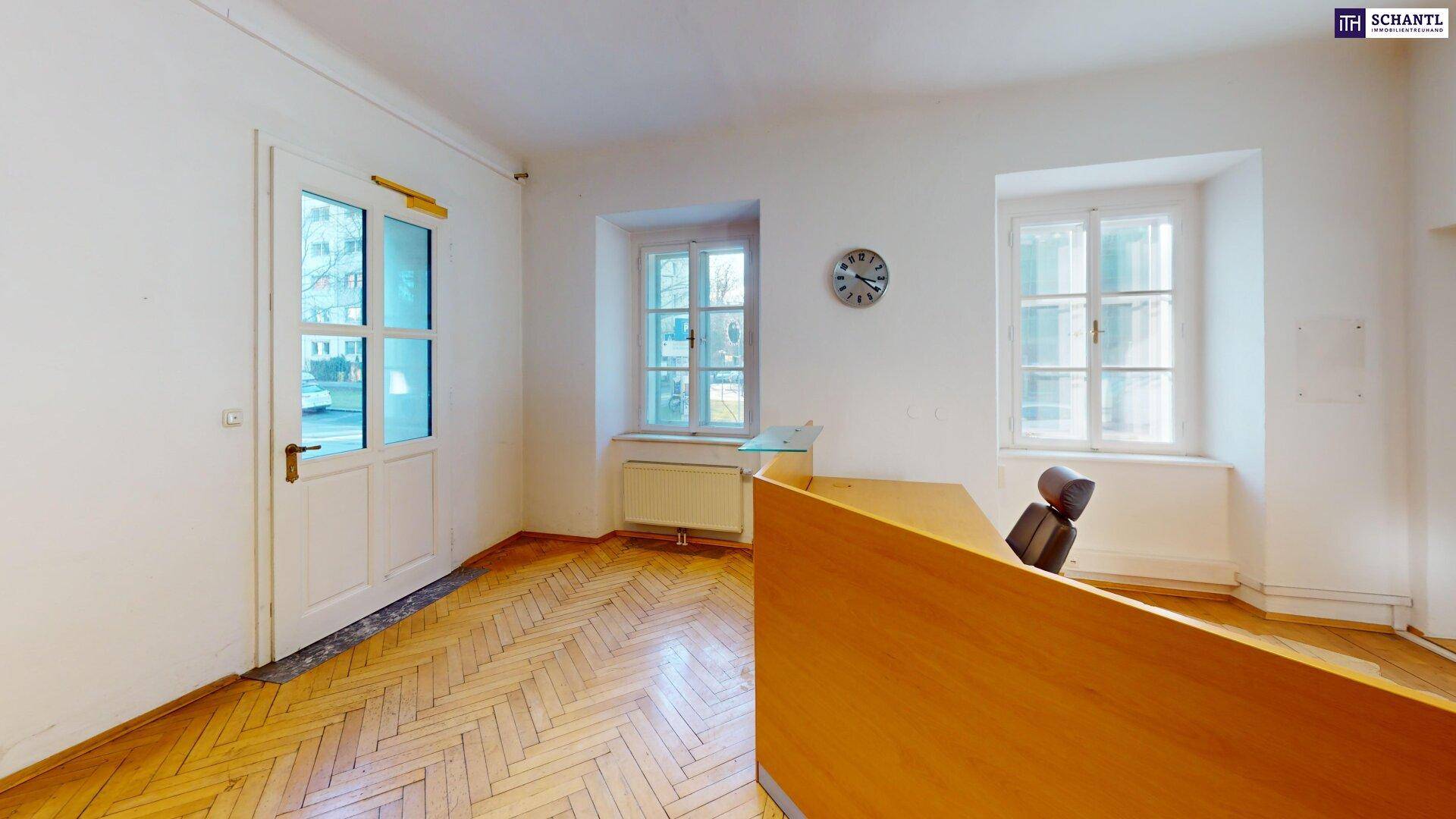 Büroraum mit Holzboden, Schreibtisch und einer Tür, die nach draußen führt, mit natürlichem Lichteinfall.