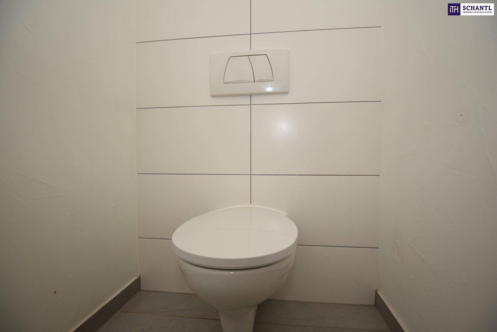 Modernes separates WC mit wandmontierter Toilette und weißen Fliesen an den Wänden.
