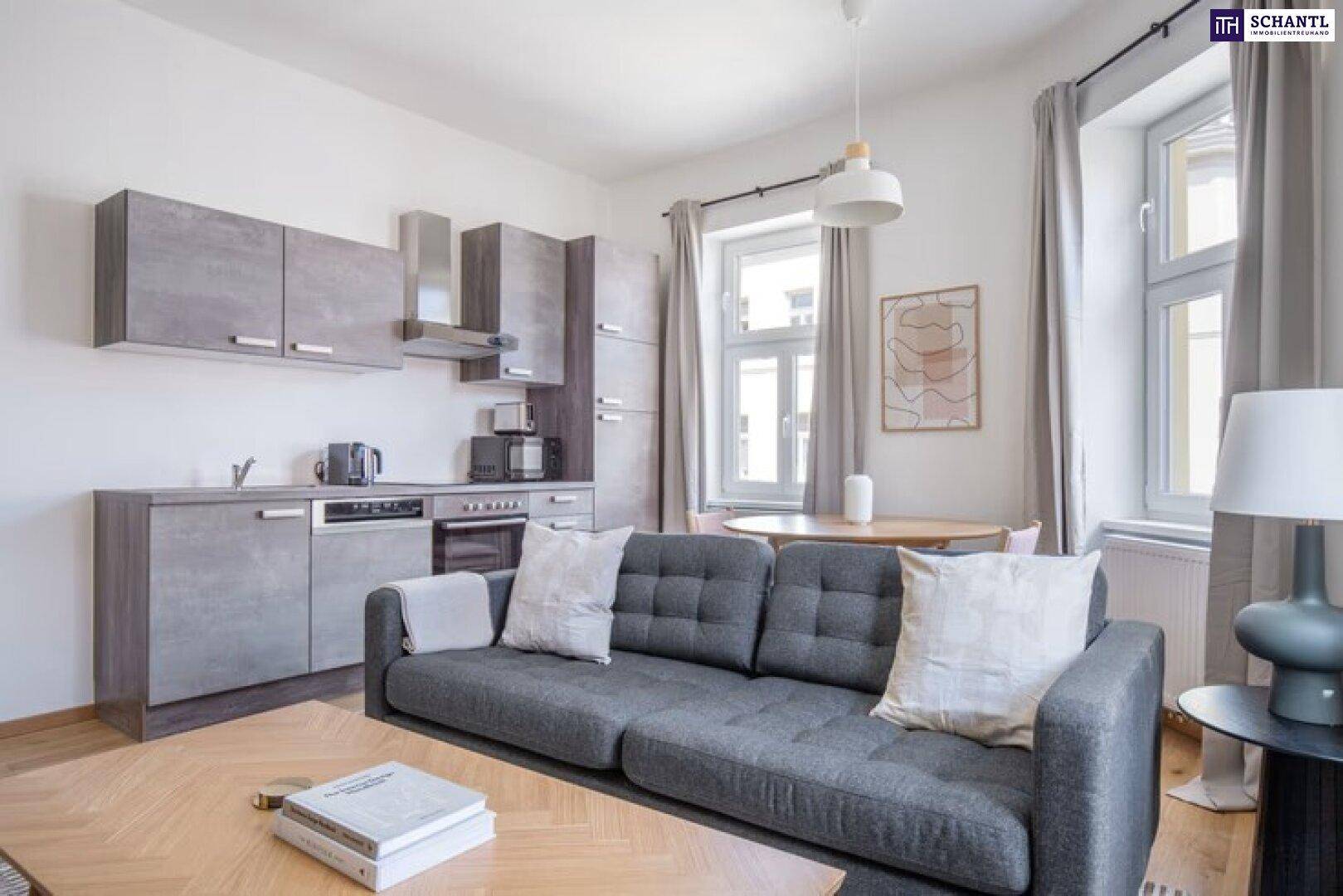 Offener Wohnbereich mit integrierter Küche, modernem Sofa und Blick auf die Stadt.