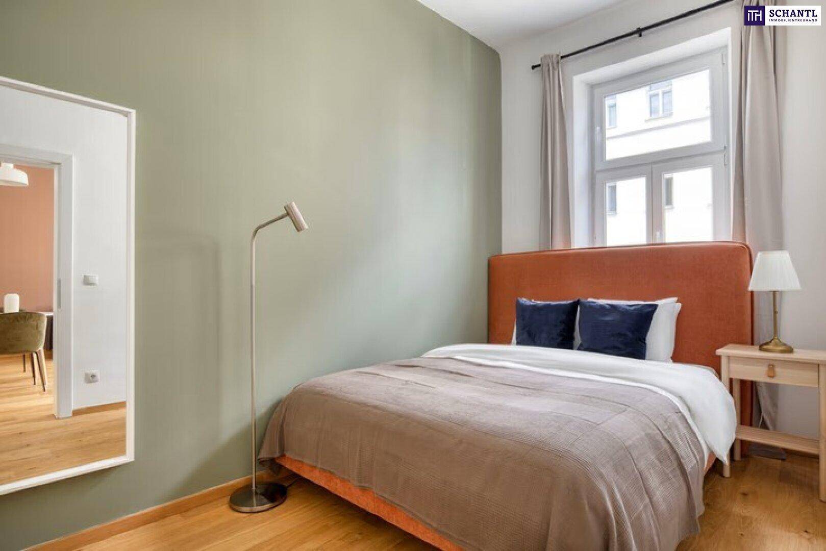 Gemütliches Schlafzimmer mit Holzboden, Fenster und einem Spiegel, der den Flur reflektiert.