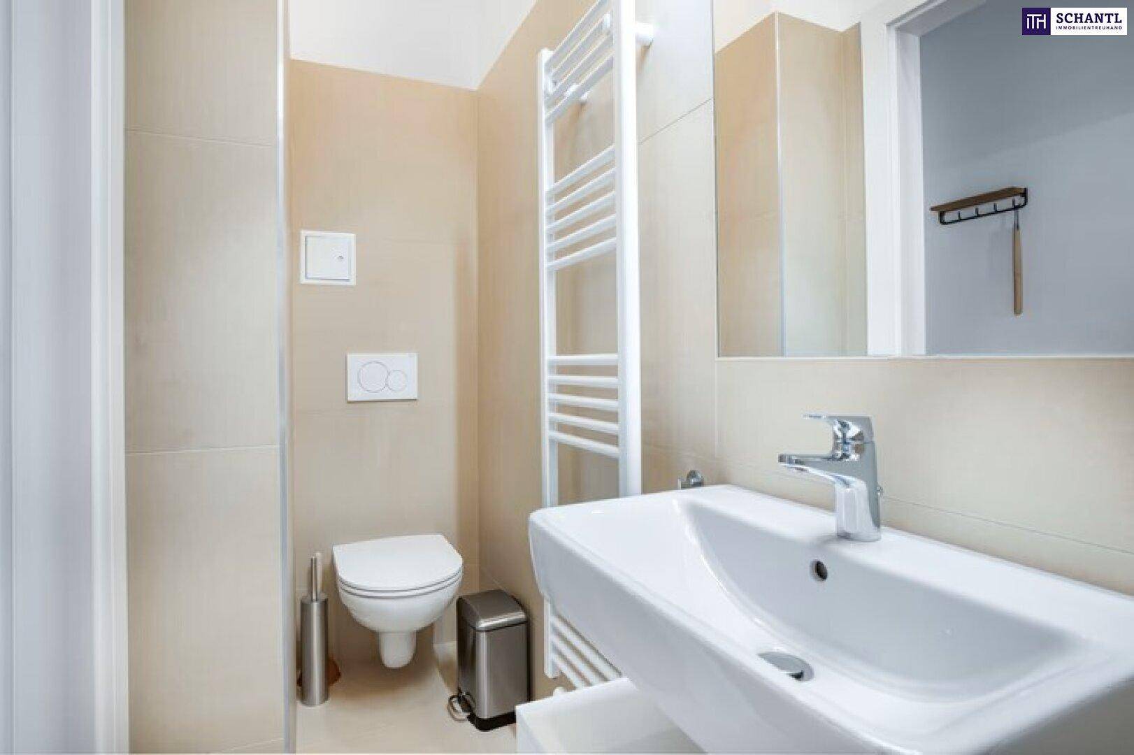Helles Badezimmer mit Toilette, Waschbecken und beheiztem Handtuchhalter in beigen Farbtönen.