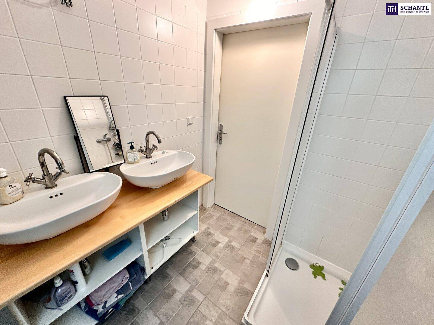 Modernes Badezimmer mit Doppelwaschbecken, Duschkabine und hellen Fliesen.