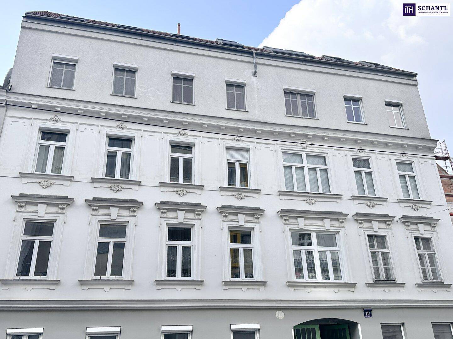 Klassische Fassade eines Altbaus mit vielen Fenstern und traditionellen Verzierungen.
