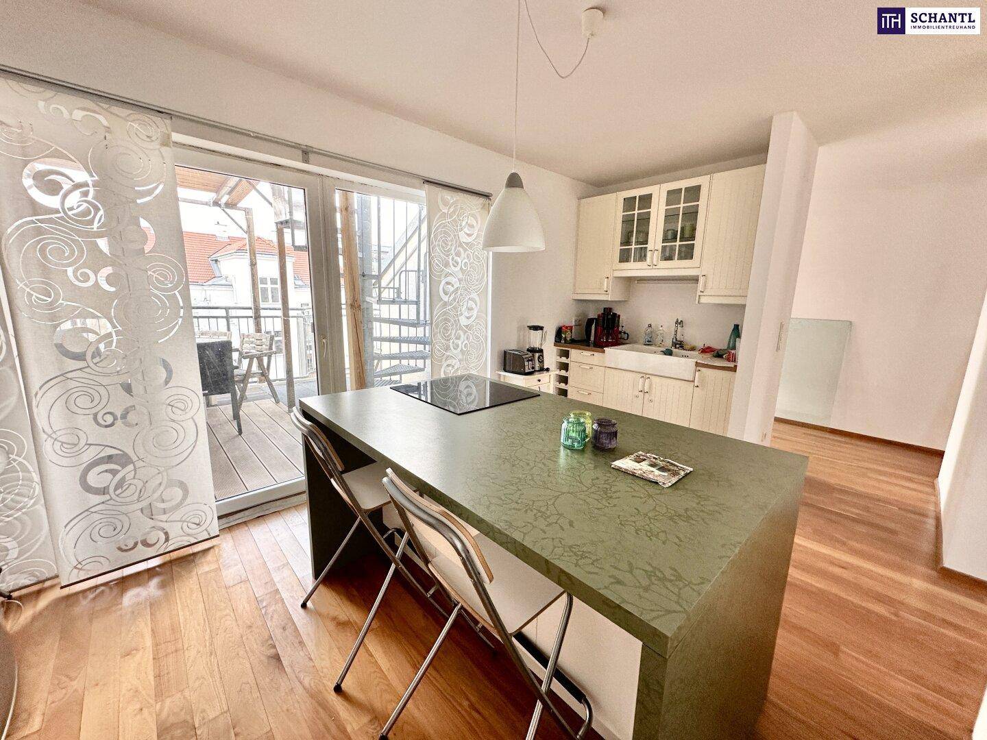 Moderne Küche mit Kochinsel, Induktionskochfeld und Zugang zu einem Balkon mit Stadtblick.