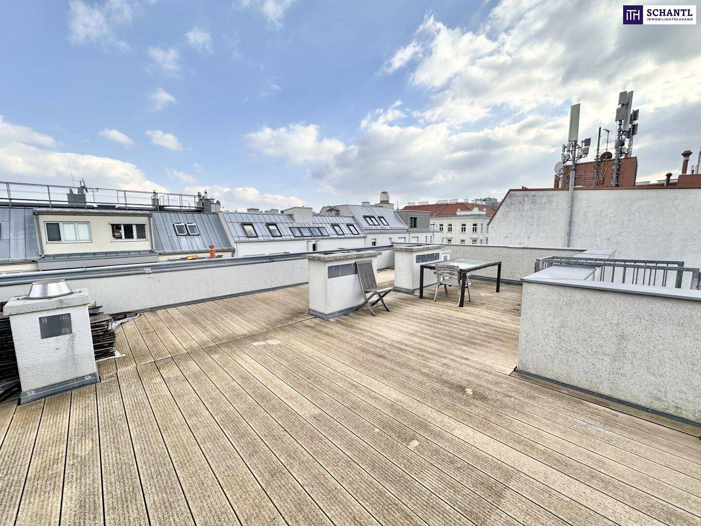 Große Dachterrasse mit Holzbelag, Esstisch im Freien und weitem Stadtblick.