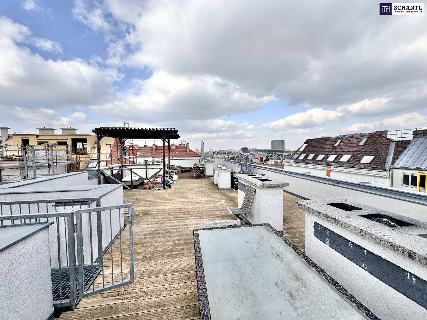 Weitläufige Dachterrasse mit Holzbelag und Panoramablick über die Stadtlandschaft.