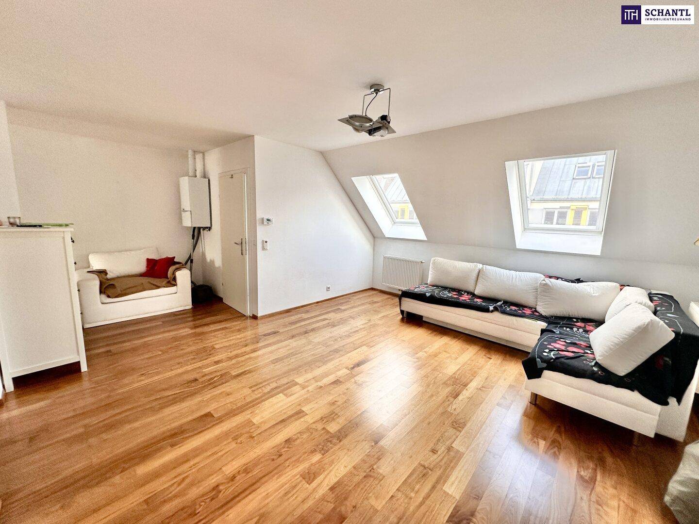 Helles Wohnzimmer mit Holzboden, gemütlichem Sofa und Dachfenstern unter einer schrägen Decke.