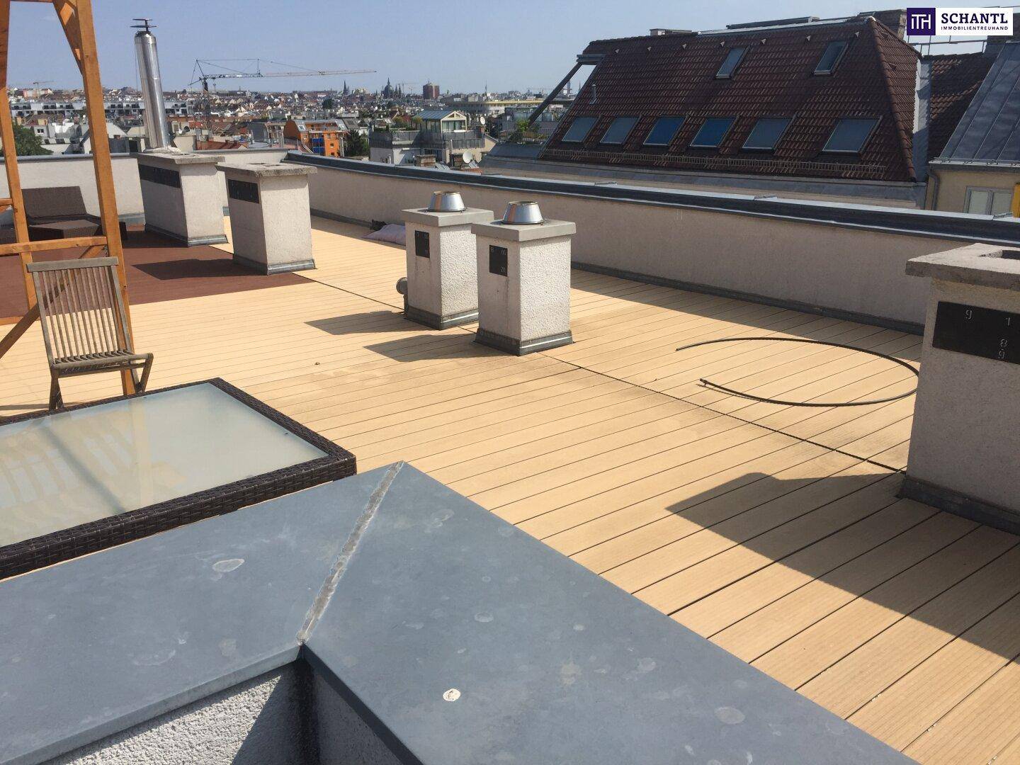 Geräumige Dachterrasse mit Holzbelag und weitem Blick über die Stadt.