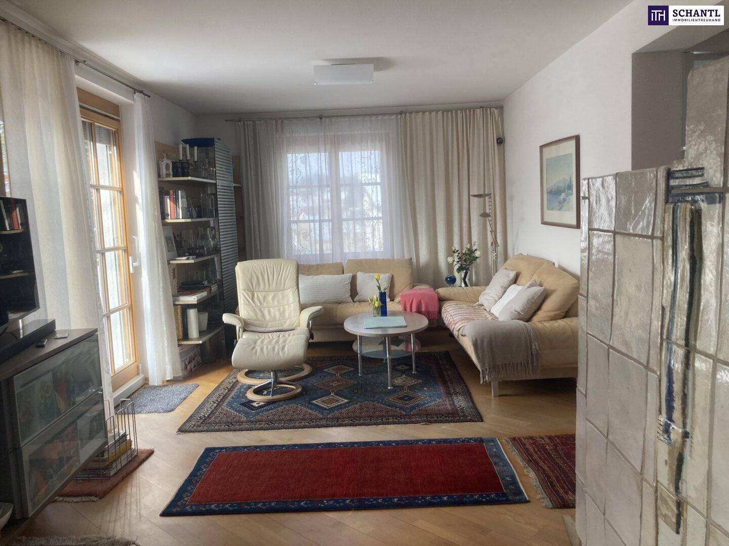 Helles Wohnzimmer mit bequemen Sofas, Sessel und einem traditionellen Kachelofen für gemütliche Stunden.