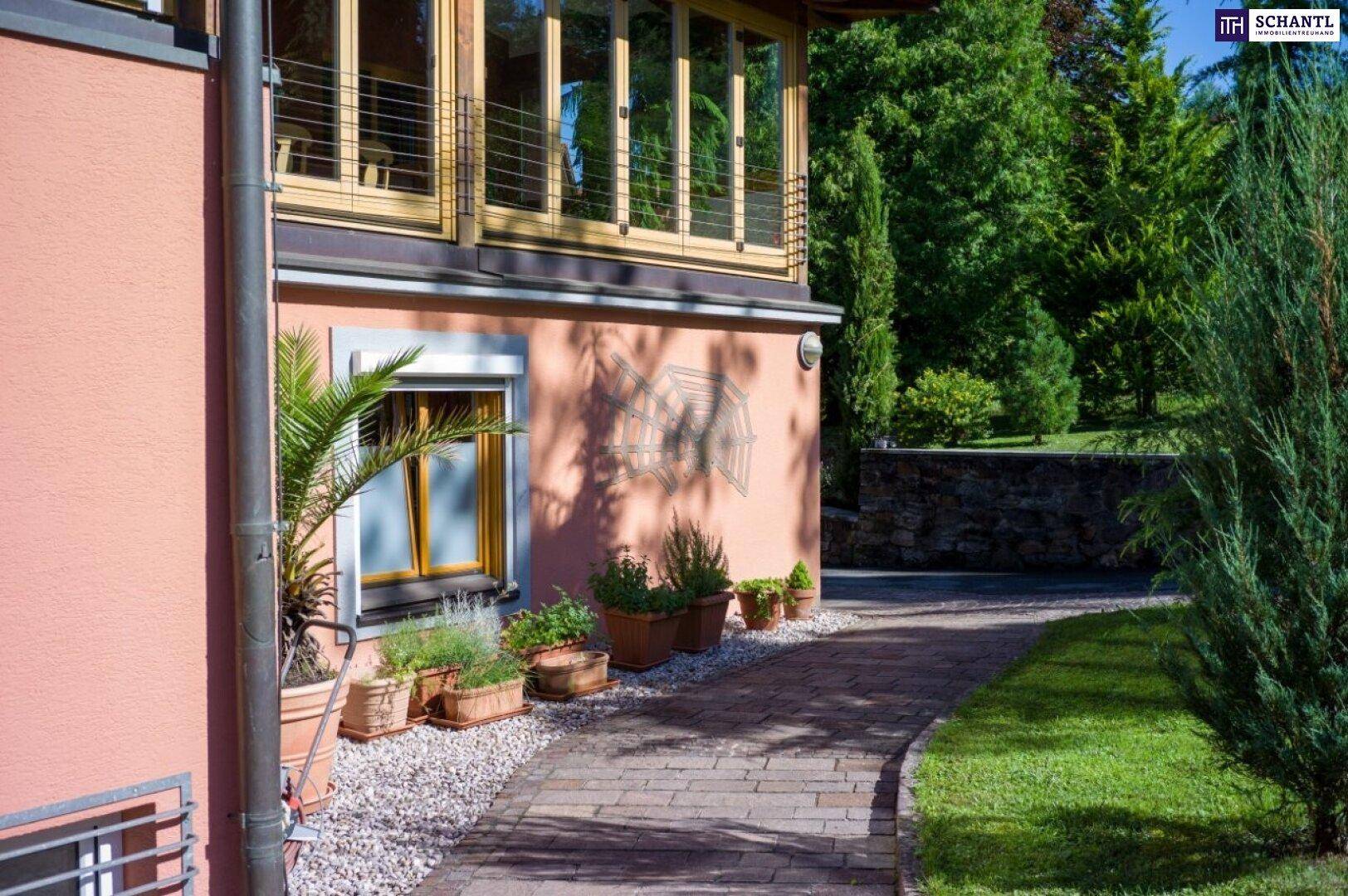 Seitenansicht des Hauses mit gepflastertem Weg, Topfpflanzen und Zugang zum Gartenbereich.