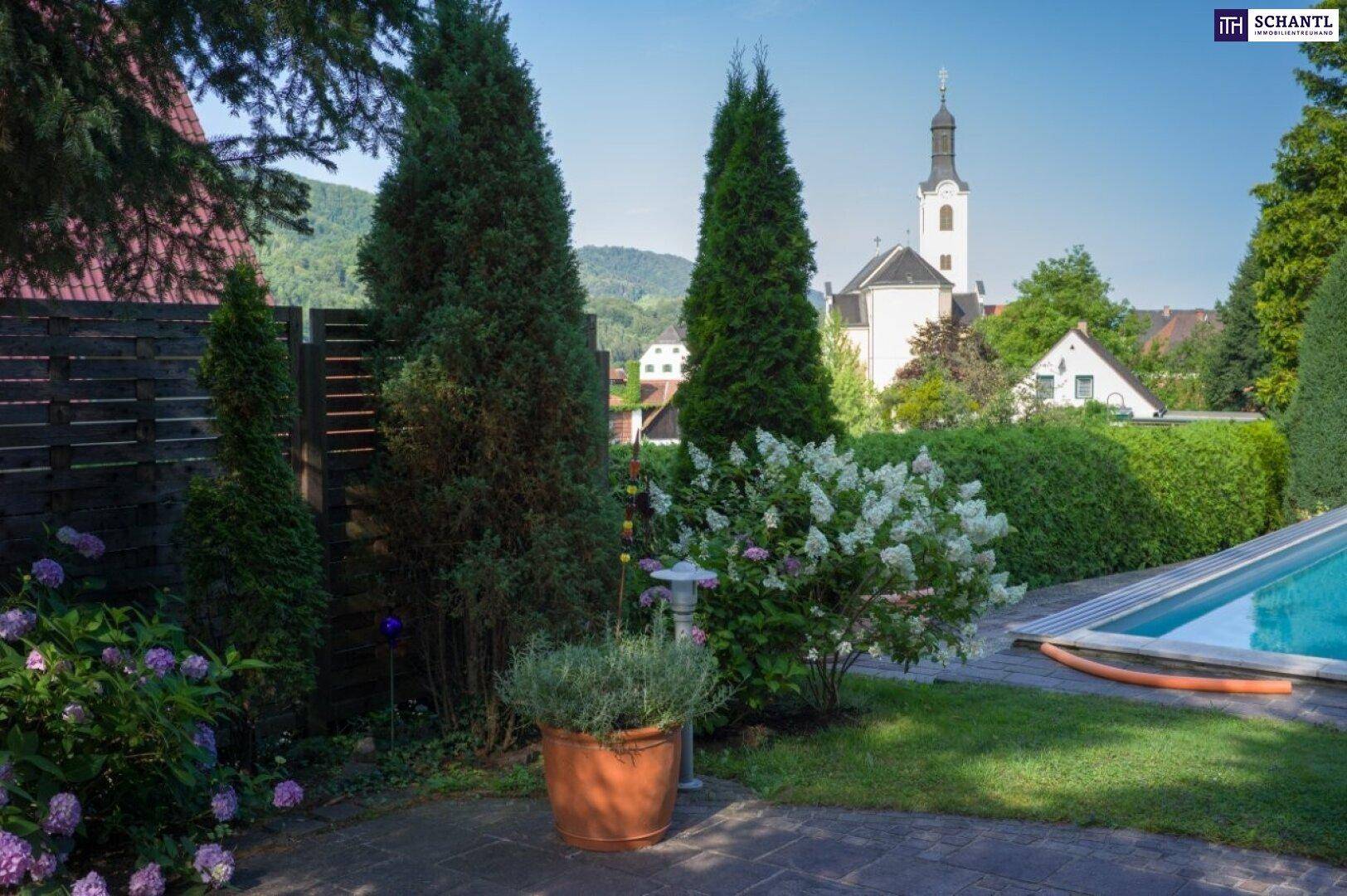 Idyllischer Gartenbereich mit Pool, üppiger Bepflanzung und Blick auf die umliegende Landschaft.