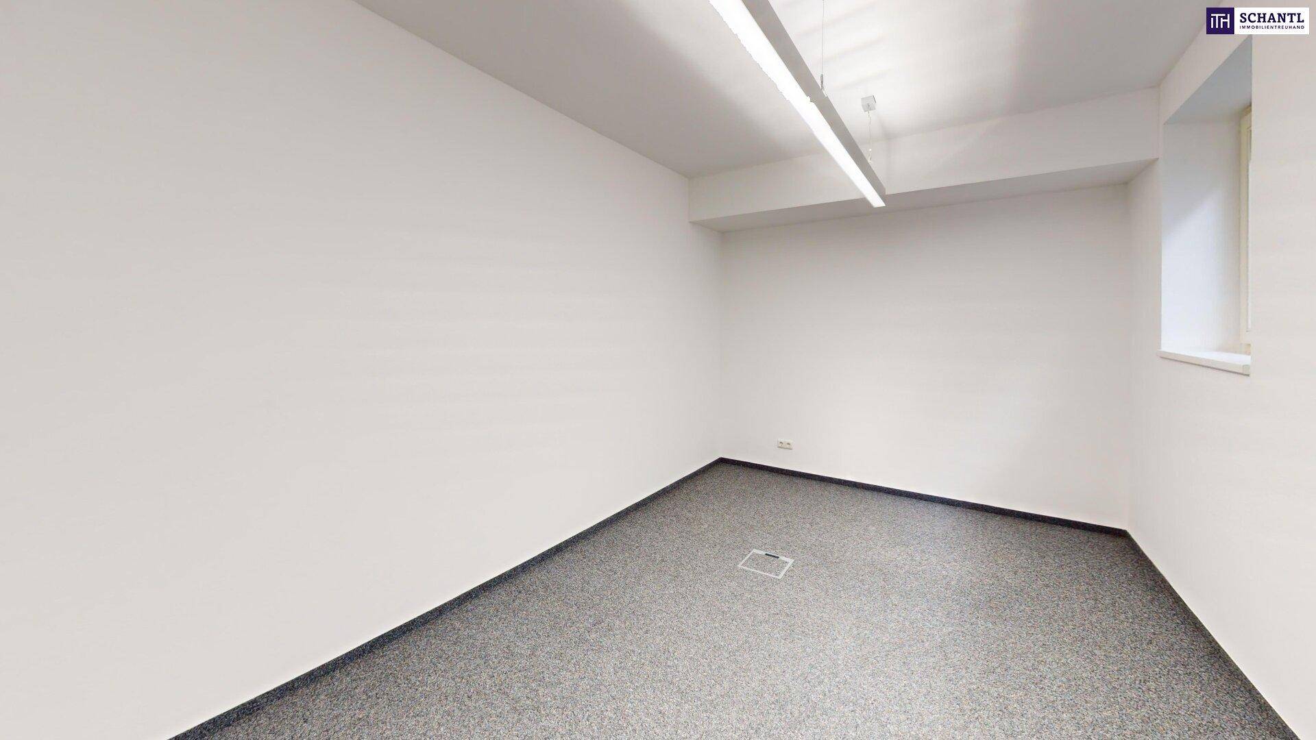Heller Büroraum mit grauem Teppichboden und einer modernen Deckenleuchte.