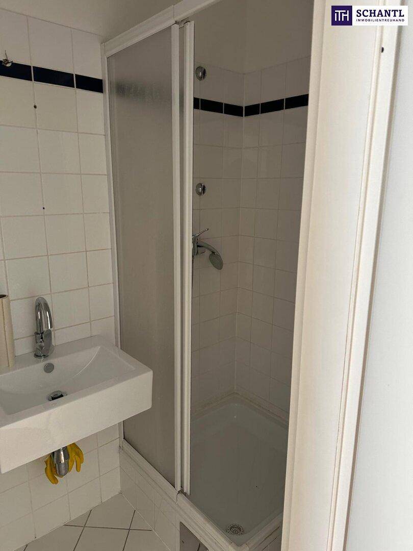 Funktionales Badezimmer mit Duschkabine, Waschbecken und weißen Wandfliesen.