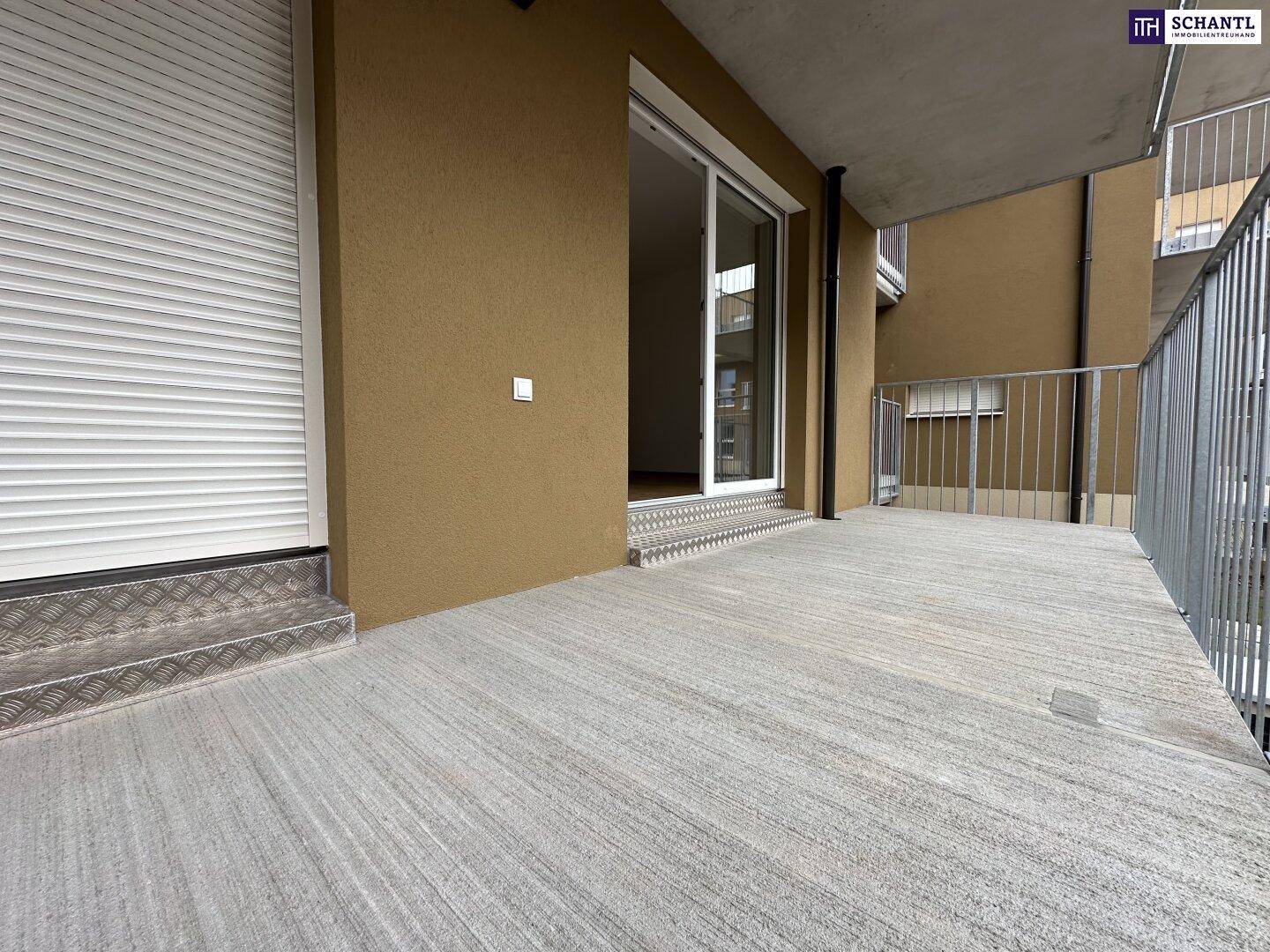 Geräumiger Balkon mit Betonboden und einer geschlossenen Rolllade an der Fassade.