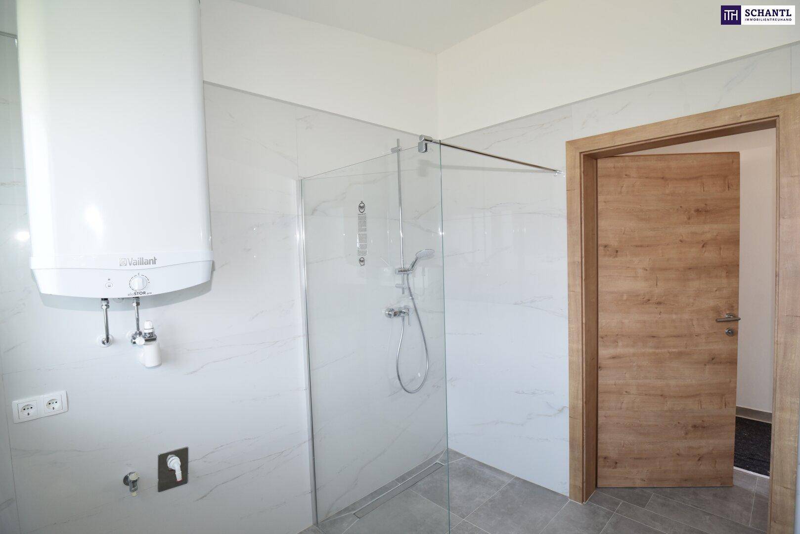 Modernes Badezimmer mit Duschkabine aus Glas und großformatigen Fliesen an den Wänden.