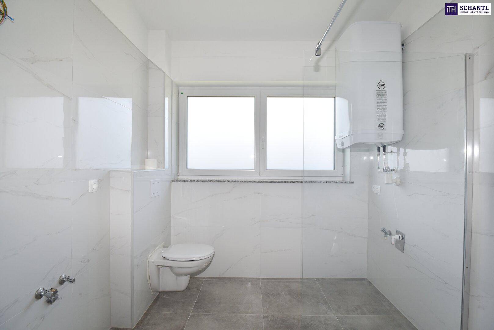 Geräumiges Badezimmer mit Wand-WC und großem Fenster, bereit für die Installation weiterer Sanitärobjekte.